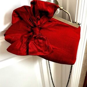 Elegant Red Clutch with Bow Accent and crossbody chain.
